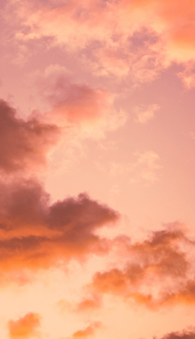 Photo d'un ciel nuageux teinté de rose et d'orangé.