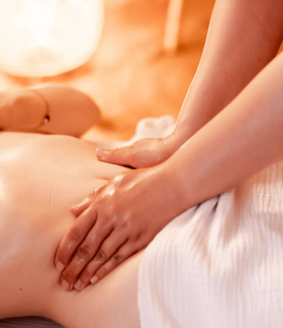 Deux mains sont posés sur les cotés du ventre d'une femme pour la masser.