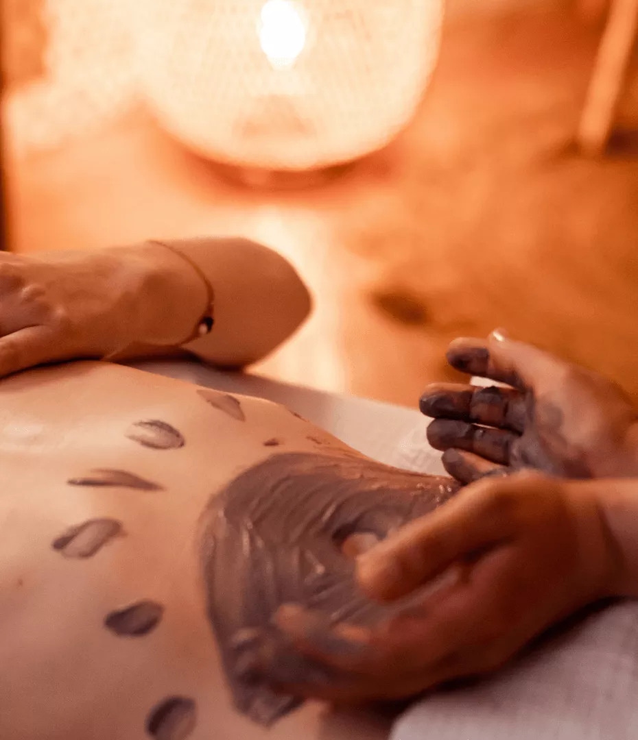 Un cataplasme de plantes et d'argiles est posé sur le ventre d'une femme.