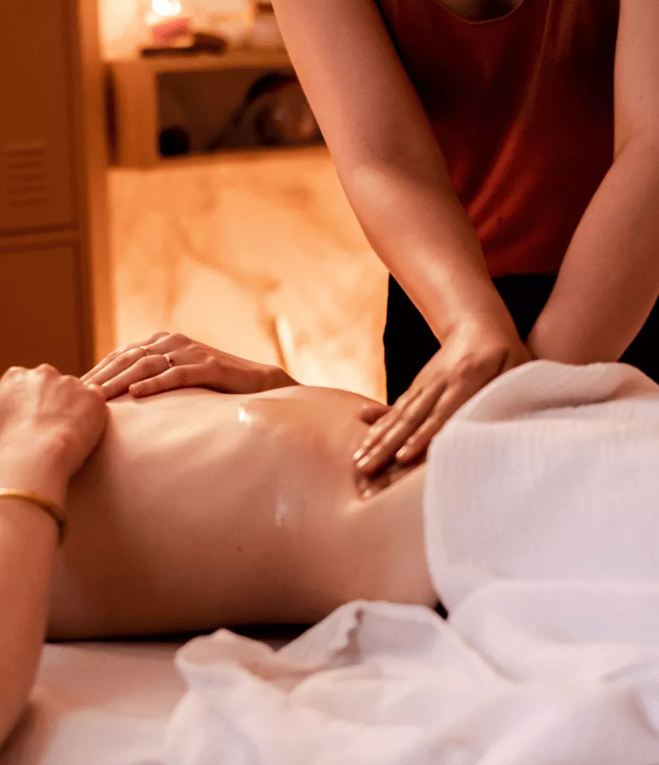 Massage du bas ventre d'une femme en mouvement circulaire avec de l'huile chaude.